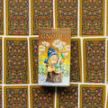 Produktų puslapyje Tarot of the Gnomes dėžutė centre, gnomis pilsto vandenį prie baltų ramunių ant dekoratyvių kortų nugarėlių