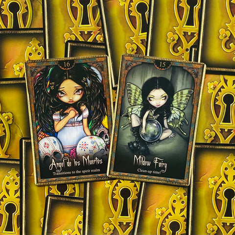 Tarot kortos — dvi atviros kortos (Angel de los Muertos ir Mildew Fairy) ant geltonų rakto formos nugarėlių, specifinis dizaino variantas