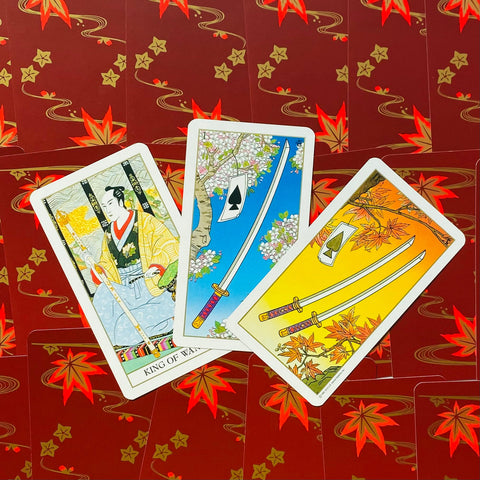 tarot kortos Japonų tema, trys atverstos kortos (Karalius ir kardai) išdėstytos ant raudonų nugarėlių