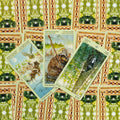 Tarot kortos — trys atverstos taurės kortos su gyvūnų iliustracijomis ant žalių raštuotų nugarėlių