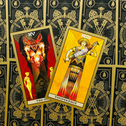 Tarot kortos – dvi kortos (Temperance geltonos ir The Devil raudonos) ant juodo auksinio nugarėlių fono, kampu išdėstytos unique variantui