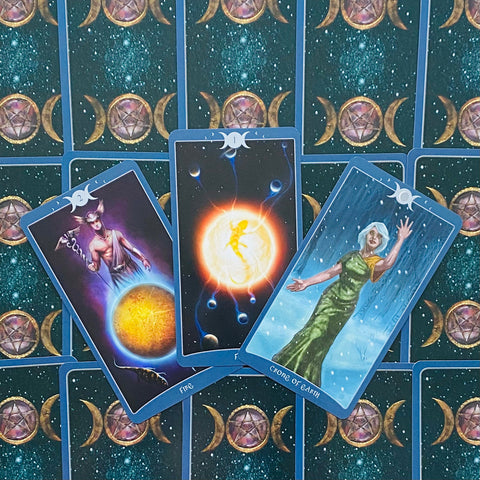 Tarot kortos mėlynomis nugarėlėmis, išskleistas trijų kortų komplektas su ryškia saulės, žemės ir Hermeso simbolika