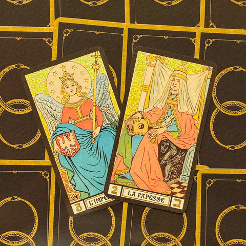 Tarot kortos klasikiniu dizainu — dvi atverstos kortos (Įpėdinė ir Papė) su auksiniu blizgesiu ir juoda nugarėle