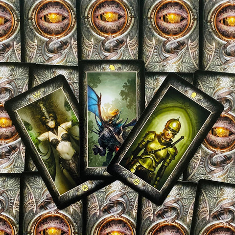 tarot kortos trys atverstos kortos su žalios ir auksinės spalvų iliustracijomis ant ornamentuotų nugarėlių