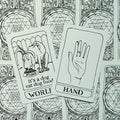 Tarot kortos su dviem atvertais "World" ir "Hand" kortomis ant juodai baltos pieštinės nugarėlės, viršaus planas