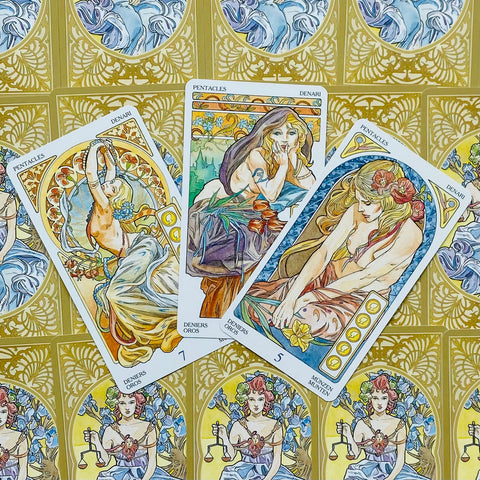 tarot kortos Art Nouveau stiliaus pentaklių trys kortos išrikiuotos ant aukso ornamentuoto nugarėlio, detaliai iliustruotos feminina figura ir gėlėmis