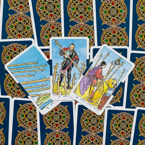 Tarot kortos Rider–Waite stiliaus, mėlynos nugarėlės su auksiniu ornamentu, trijų Lazdų kortų išklotinė iš viršaus