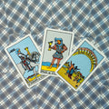 Tarot kortos trijų kortų komplektas — Riteris, Puslapis ir Dešimt taurų ant mėlyno, tinkuoto raštuoto fono, parduotuvei skirtas kampinis kadravimas