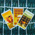 Tarot kortos Pentakliai: trys kortos su oranžine lape, auksiniais ženklais ir žaliais žvaigždėtais nugarėlių raštais