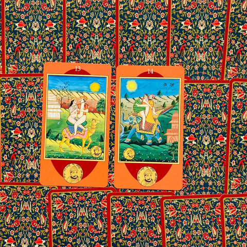 Tarot kortos — oranžiniais rėmeliais pažymėtos 13 ir 14 kortos su Indijos stiliaus iliustracijomis ant gėlėto tamsiai mėlyno nugarėlio