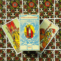 RWS tarot kortos Pamela Colman Smith baltame dėkle centre, dvi atverstos kortos šone ant ornamentuoto fono