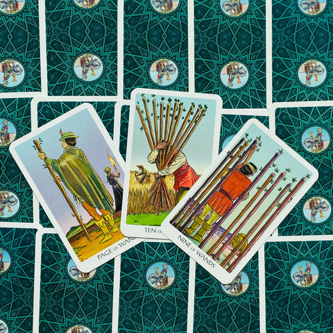 Tarot kortos Rider–Waite, trimis atverstomis ietų kortomis (Page, Nine, Ten) ant turkio raštuoto nugarėlio