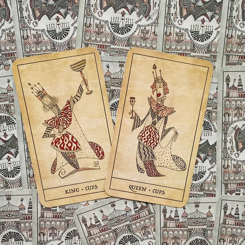 Taro kortos King ir Queen of Cups, kreminio atspalvio iliustruotos kortelės ant dekoratyvaus galinio rašto, poros išdėstymas