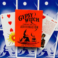 Gypsy Witch kortos raudoname dėkle su juoda raganos iliustracija, šalia atverstos kortelės su raudonomis širdimis