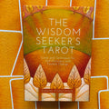 Tarot kortos The Wisdom Seeker's, autoriaus David Fontana, oranžinės dėžutės priekinis viršelis su stylizuotais medžių motyvais ir šiltu geltonu fonu