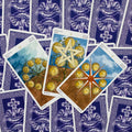 Tarot kortos violetinėmis nugarėlėmis — trys išskleistos Pentaklių kortos (8, 9, 10) su auksiniais motyvais ir smulkiais piešiniais peržiūrai