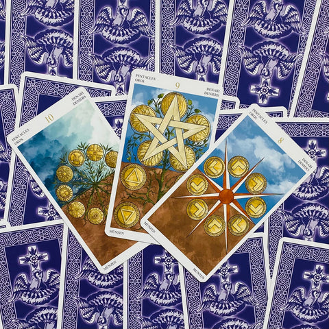 Tarot kortos violetinėmis nugarėlėmis — trys išskleistos Pentaklių kortos (8, 9, 10) su auksiniais motyvais ir smulkiais piešiniais peržiūrai