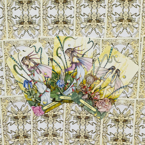 tarot kortos fėjų tema, trys atverstos kortos su gėlių iliustracijomis ant ornamentinio nugarėlių fono, parodo dizaino variantą