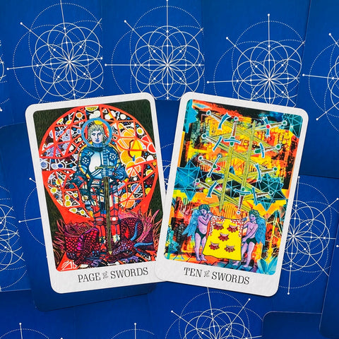 Tarot kortos – spalvingas iliustruotas komplektas, matomi Page of Swords ir Ten of Swords priekiniai paveikslėliai bei mėlyni ornamentuoti nugarėliai