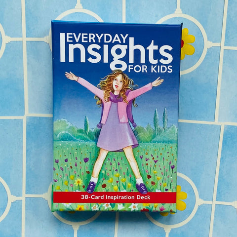 Inspiracijos kortų rinkinys Everyday Insights for Kids mėlyname dėkle, 38 kortos, priekyje mergaitės iliustracija ant gėlių pievos, stalo raštu fonui kontrastuojant