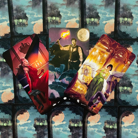 Tarot kortos su trimis atversto dizaino kortomis — raudona pianistė, vyras su fakelu ir žalia panelė ant karuselės, kortų nugarėlė su mėnulio pilimi