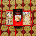 Tarot kortos Sexual Magic raudoname dėkle, centrinis planas su dviem iliustruotomis kortomis šonuose ir aukso ornamentais
