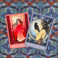Orakulo kortos — dvi demonstracinės kortos Red Queen (raudona) ir Raven Goddess (mėlyna), pasuktos ir persidengusios ant ornamentuoto audinio fono