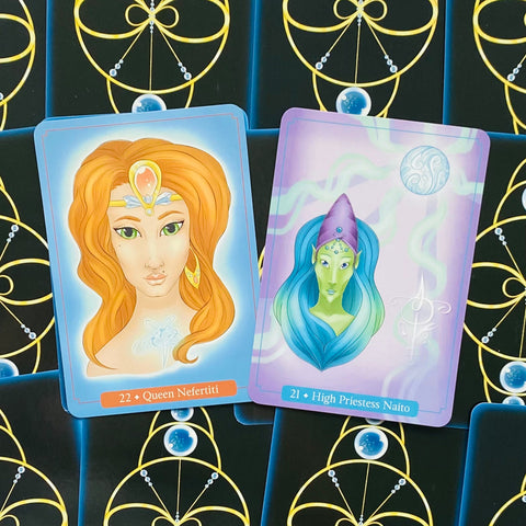 Tarot kortos su atvertais priekiais, rodantys Queen Nefertiti oranžinę ir High Priestess Naito mėlyno‑žalią kortas ant juodai‑auksinio fono