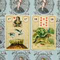 Lenormand kortos, dvi atverstos kortos (17 Žąsys ir 18 Šuo) ant mėlyno angelų fono, rodoma dviejų kortų išklotė poroms