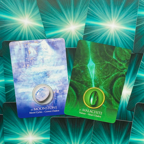 oracle kortos — artimas kadras su mėlyna Moonstone (Crown Chakra) ir žalia Malachite (Heart Chakra) kortomis ant žalių nugarėlių