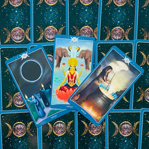 tarot kortos mėlynu kraštu, trys atverstos „Water“ kortos — lotoso dievybė su drambliais, užtemimo scena ir raganos katilas ant triple‑moon nugarėlių