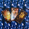 Tarot kortos trijų kortų išklotė su ryškiomis, siužetinėmis kortomis centre ant mėlynų nugarėlių