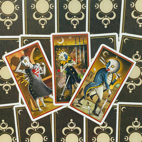 Tarot kortos rinkinys: trys atverstos kortos (III, IV, V) su siurrealistinėmis figūromis ant tamsių ornamentuotų nugarėlių