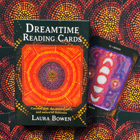 Dreamtime kortų rinkinys juodoje dėžutėje su ryškia oranžine ir violetine taškine mandala, šalia atversta Moon (Mėnulis) korta