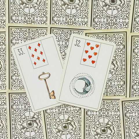 Lenormand kortos: dvi atidengtos kortos — Raktas ir Mėnulis — gulsčiai ant dekoratyvių nugarėlių, artimas planas