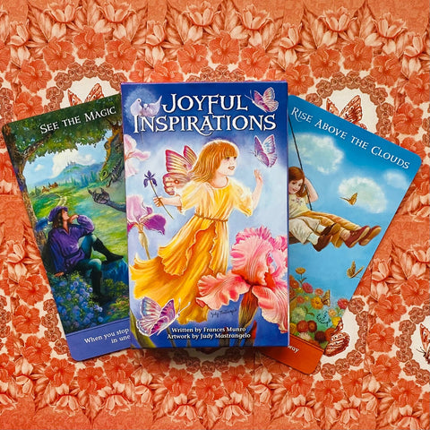 Įkvėpimo kortų rinkinys Joyful Inspirations mėlyname dėkle su geltona fėjų figūra, trys kortos išdėstytos ant raudono gėlių fono