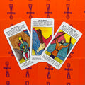 Tarot kortos su ryškiai oranžine nugarėle, trys kortos atvertos (Ace of Wands, Two of Wands, King of Cups) plokščias viršaus vaizdas