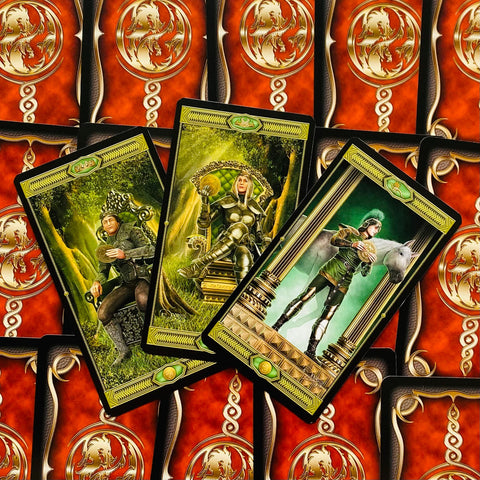 Tarot kortos su žalio‑aukso iliustracijomis, trys išskleistos kortos (monetos, ruda‑raudonos nugarėlės)