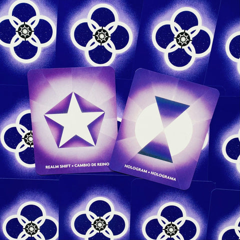 Orakulų kortos su violetinėmis nugarėlėmis ir dviem atverstomis kortomis centre – žvaigždė (Realm Shift) ir holograma (Hologram)