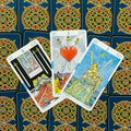 Tarot kortos Rider–Waite stiliaus, trys kardų kortos (2, 3, 4) išdėstytos vėduoklėje ant tamsiai mėlynos ornamentuotos nugarėlės