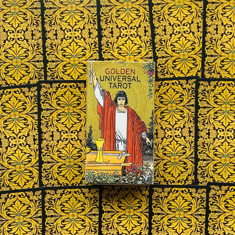 Produktų puslapyje: Golden Universal Tarot dėžutė vertikaliai su mago figūra raudonais rūbais, apsupta aukso ornamentuotų kortų nugarėlių