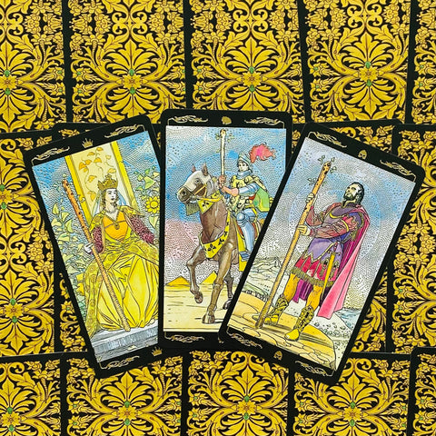 tarot kortos su aukso ornamentų nugarėlėmis, trijų atverstų Rider‑Waite kortų fragmentas centre, detalus priartinimas