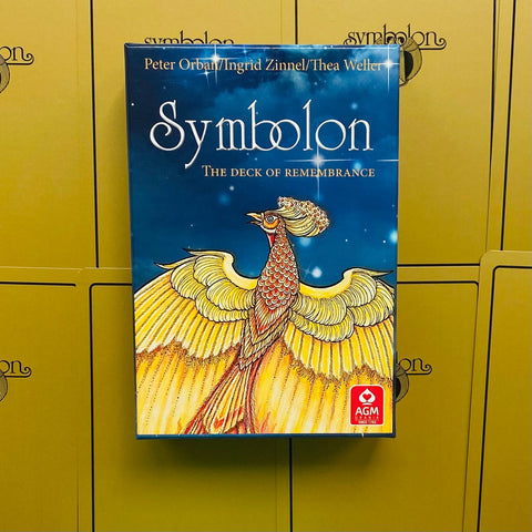 Symbolon kortų rinkinys su mėlyna dėžute ir aukso fenikso iliustracija, AGM logotipas apačioje