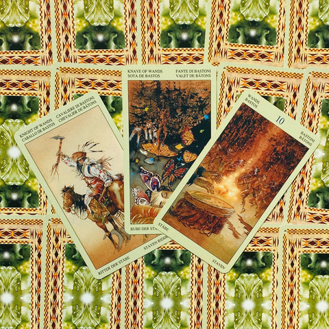tarot kortos trijų kortų išklotinė kampu — Riteris, Būrys ir 10 lazdų ant žalsvai oranžinio ornamentuoto fono