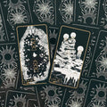 Tarot kortos juodo fono su auksiniais raižiniais, dvi atvertos kortos iš viršaus, matomas unikalus nugarėlės saulės raštas
