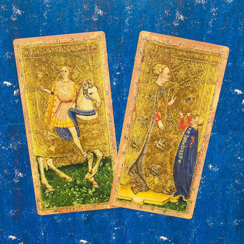 Tarot kortos auksuotos su viduramžiškomis iliustracijomis, dvi kortos (raitelis ir moteris) ant mėlyno fono