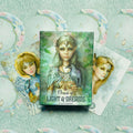 Oracle of Light & Dreams kortų rinkinys Scot Howden, žalsvai mėlyna dėžutė centre su dviem išskleistomis kortomis ant mėnulio rašto fono