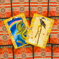 Tarot kortos su dviem kortomis: žalia gyvatė ir varnėnas ant lazdos, ryškūs geltoni rėmeliai ant raudono rašto