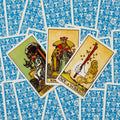 tarot kortos Rider–Waite rinkinys: trys atverstos kortos (Ace of Wands, karalius ir karalienė) ant mėlynos raštuotos nugarėlės
