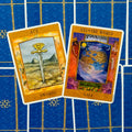 tarot kortos Gaia, atverstos Ace of Swords ir XXI The World kortos ant mėlyno ornamentuoto fono, matomas kortų priekinis dizainas